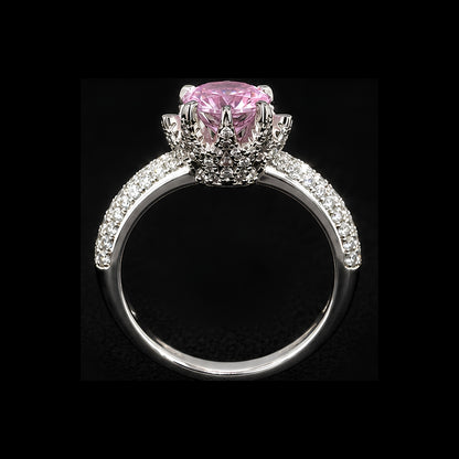 A silver-tone ring with a large pink CZ stone and smaller clear stones, set in a delicate filigree design.