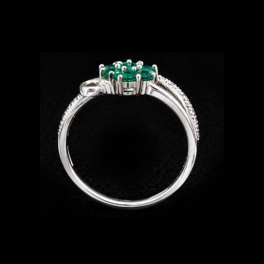 A silver ring with an emerald stone, set in a floral design.