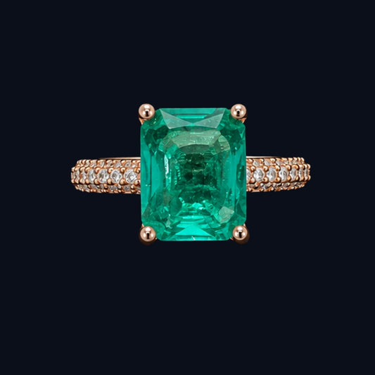 A close-up shot of an emerald green ring with a geometric design and rose gold tone, set against a dark background.