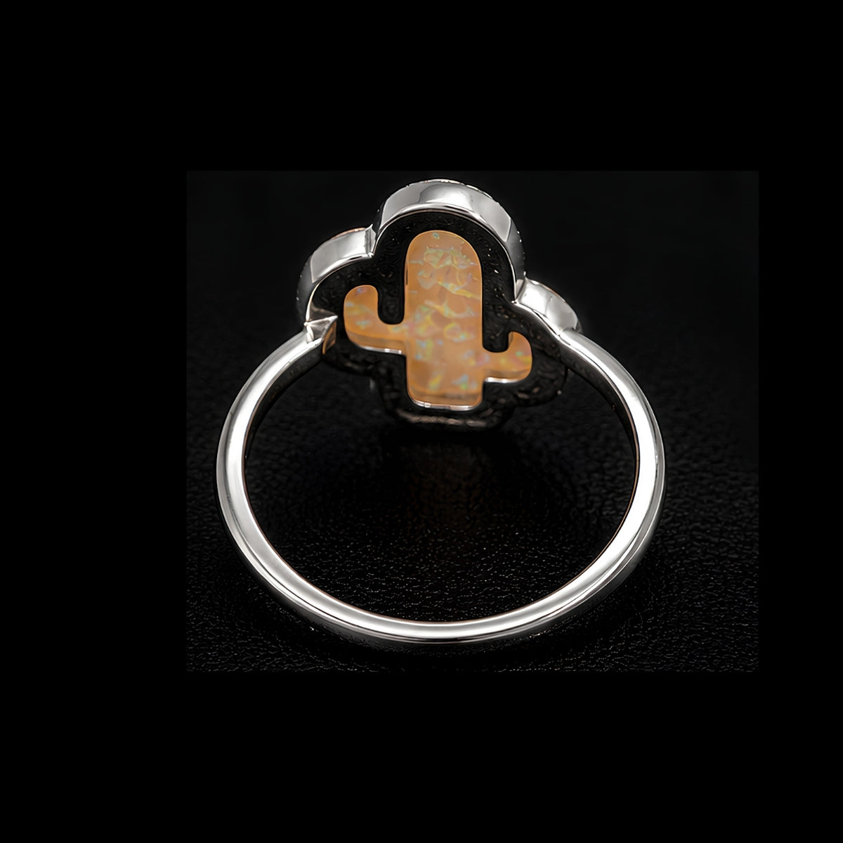 A silver ring with a cactus design on a black background