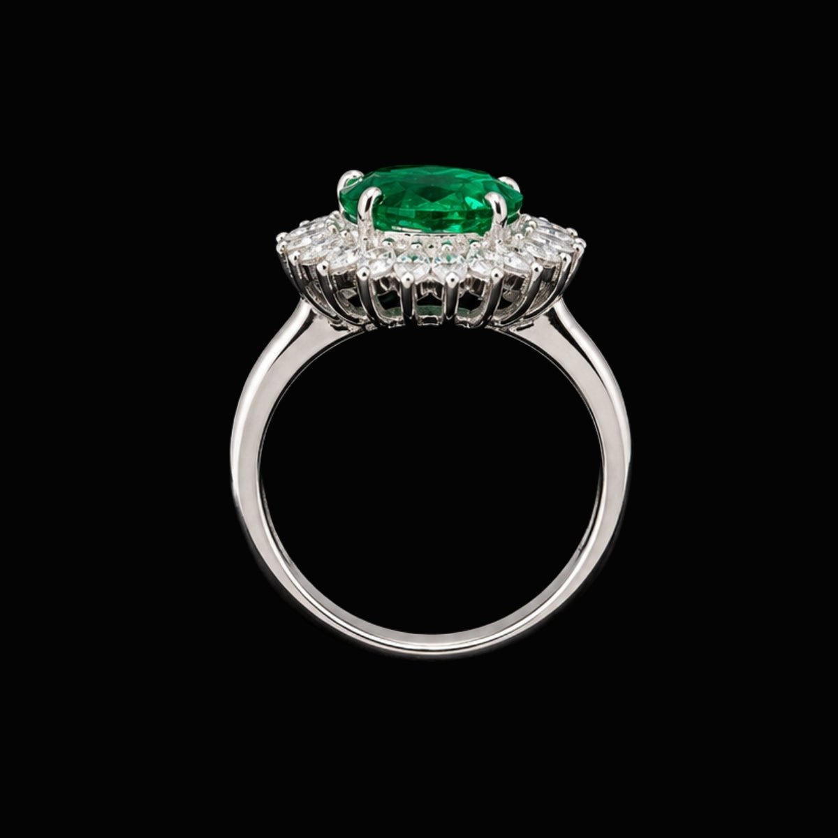 A silver ring with an emerald gemstone and CZ stones on a black background.