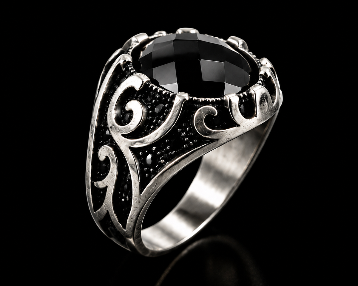 A silver ring with a large black gemstone and engraved design.