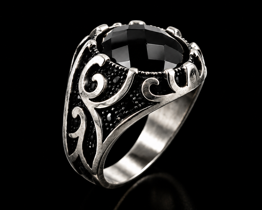 A silver ring with a large black gemstone and engraved design.