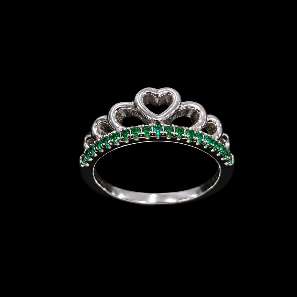 A silver-tone ring with a heart motif at the top of a crown design, adorned with green CZ stones.