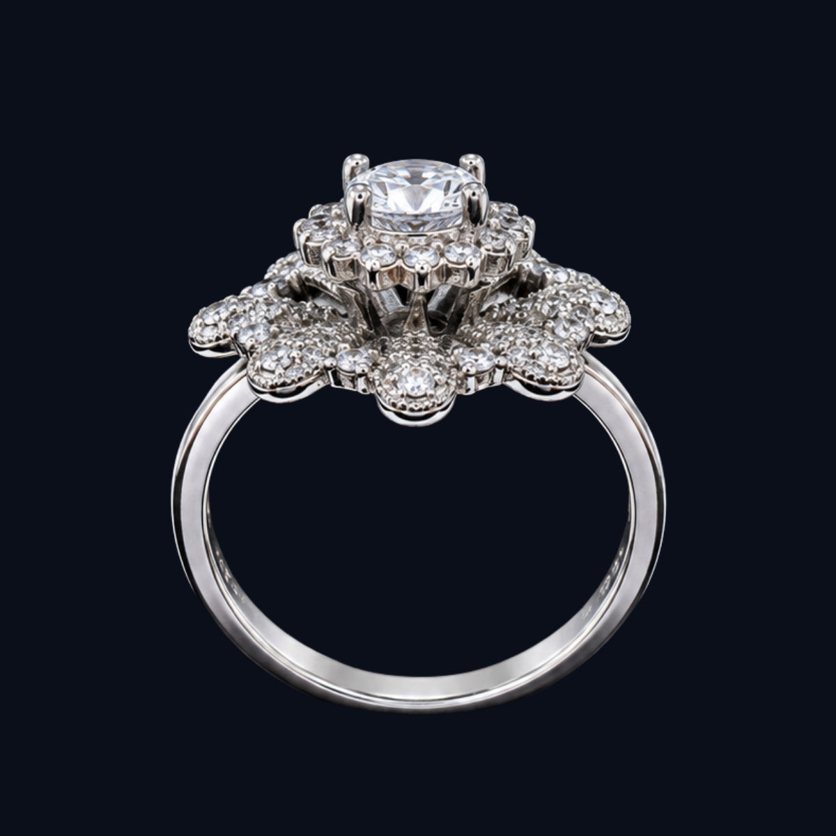 A silver ring with a floral design and CZ stones, set against a dark background.
