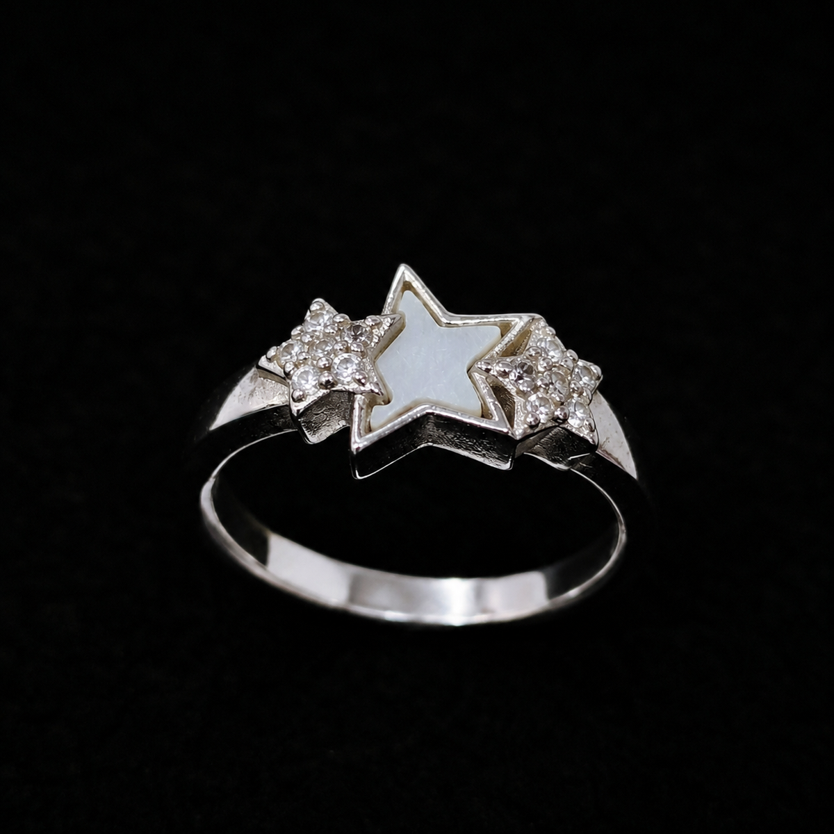 A silver-tone ring featuring two stars, one with white enamel and the other with CZ stones.
