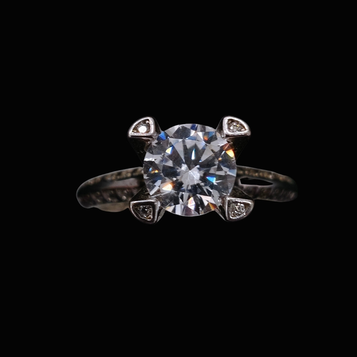 A silver-tone ring with a large round-cut CZ stone and four smaller CZ stones in a delicate setting.