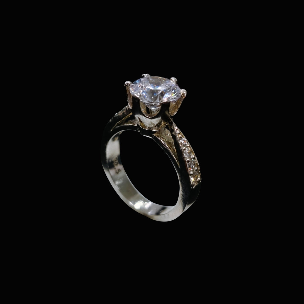 A silver-tone ring with a large, clear cubic zirconia stone at its center, surrounded by smaller stones along the band.