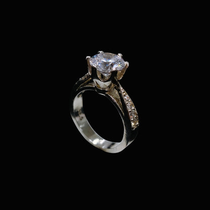 A silver-tone ring with a large, clear cubic zirconia stone at its center, surrounded by smaller stones along the band.