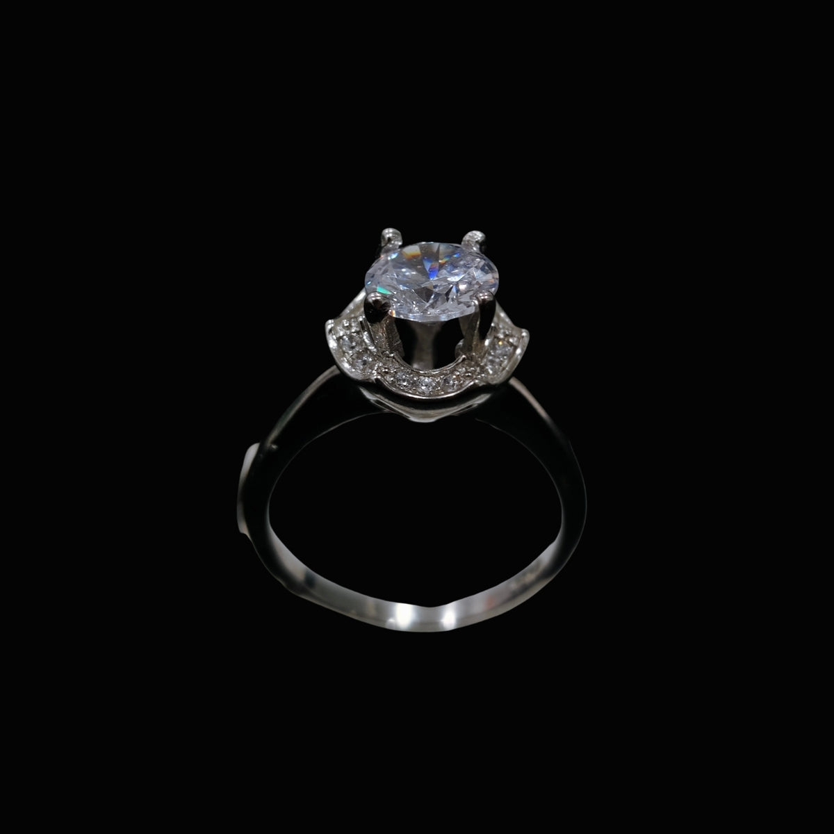 A silver-tone ring with a round-cut CZ stone on a black background