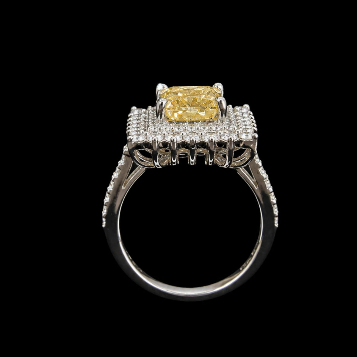A silver ring with a yellow CZ stone and clear CZ halo on a black background