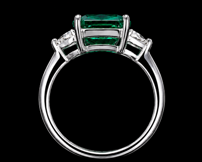 A silver ring with an emerald stone and two CZ stones on either side.