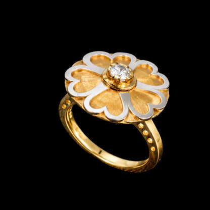 A gold and silver flower ring with a CZ stone at its center, set against a dark background.