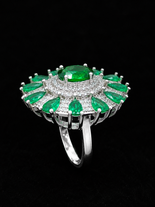 A silver ring with an emerald centerpiece and CZ accents.
