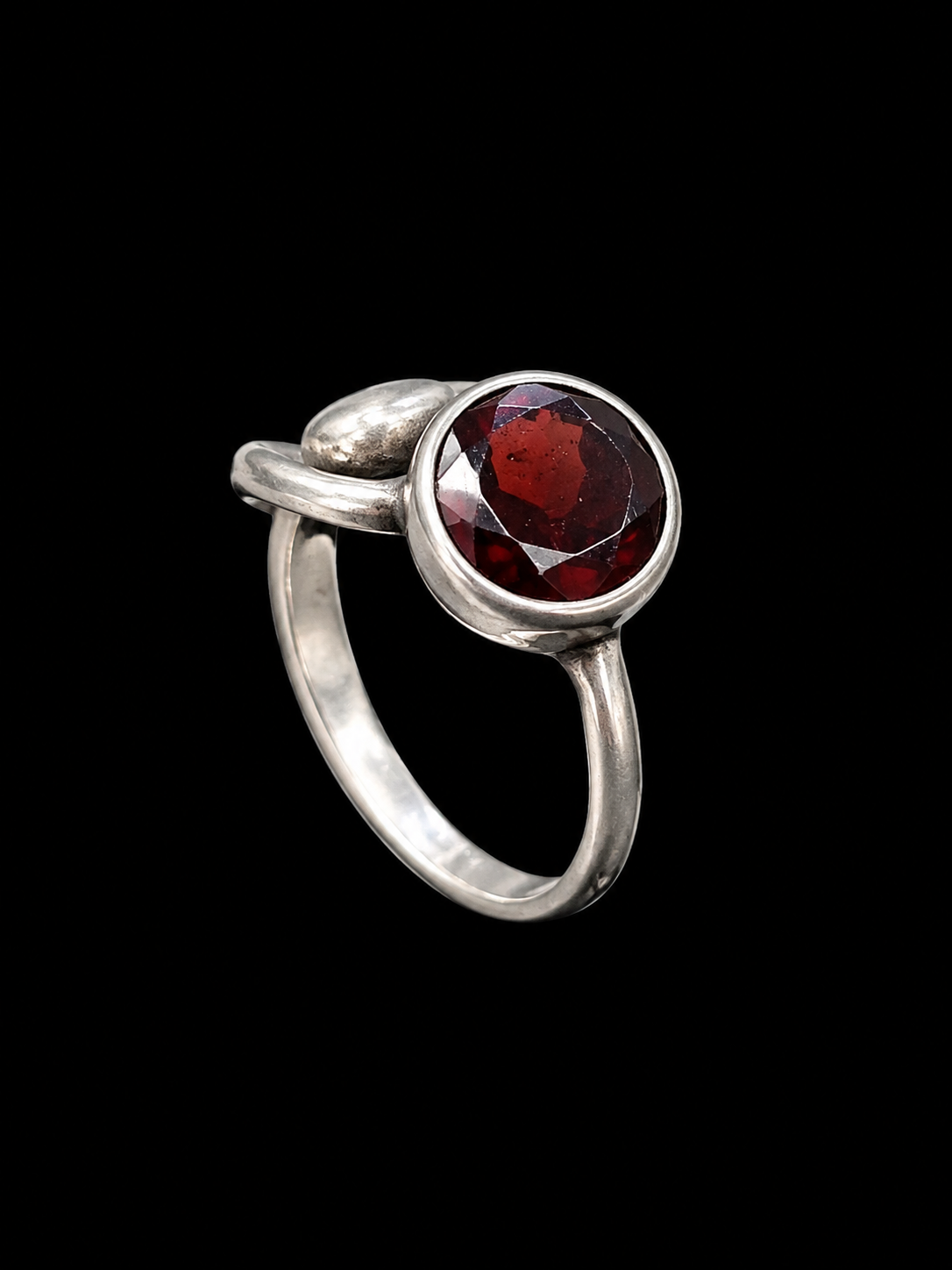 A silver-tone ring with a round garnet stone