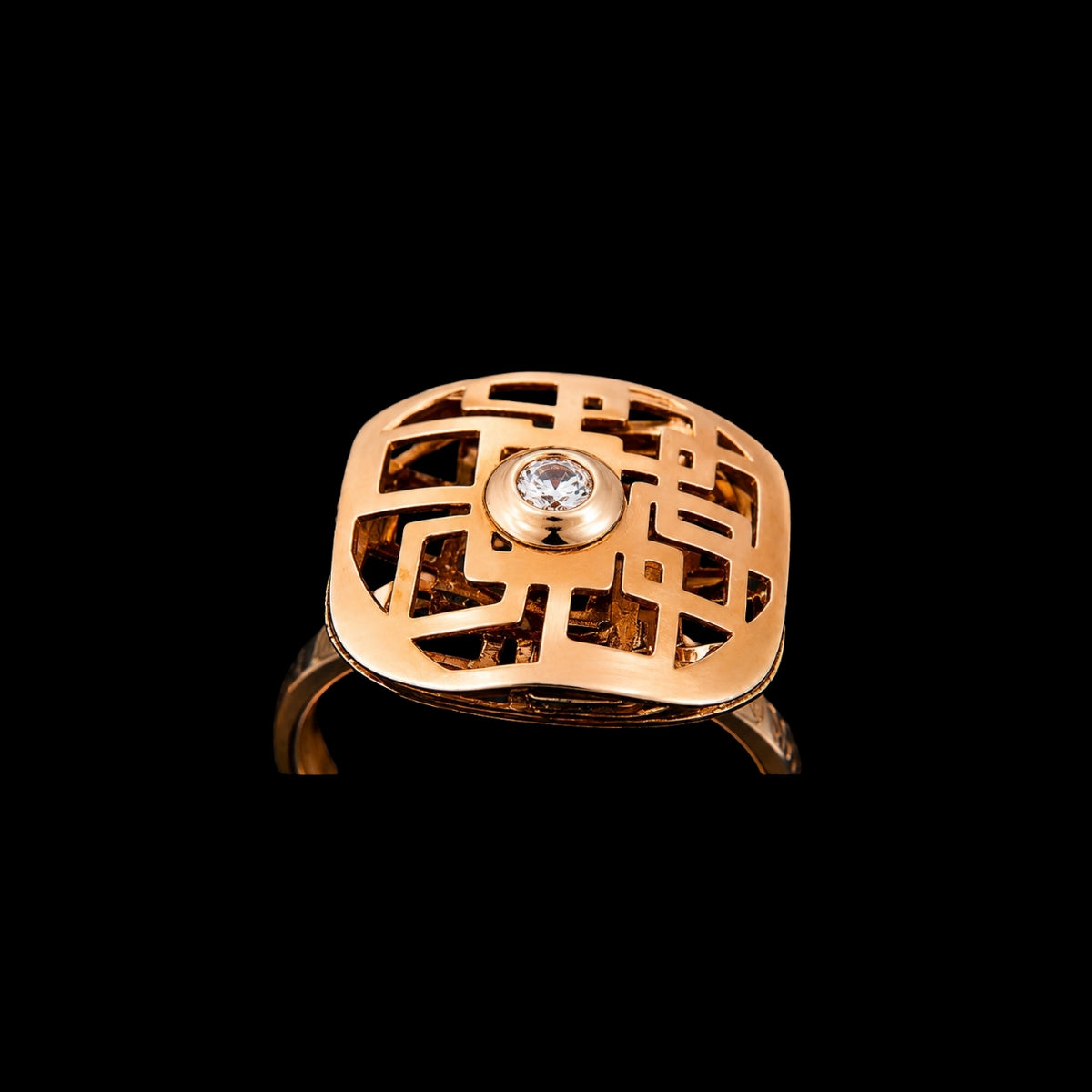 A gold tone ring with a CZ stone and an intricate design.
