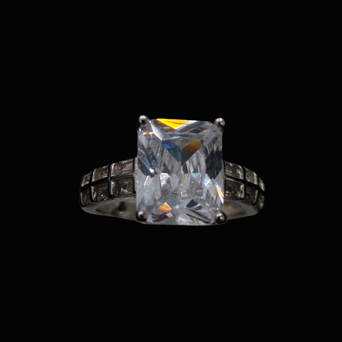 A silver ring with a large cubic zirconia stone set in a geometric design.