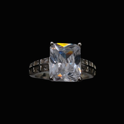 A silver ring with a large cubic zirconia stone set in a geometric design.