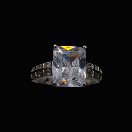 A silver ring with a large cubic zirconia stone set in a geometric design.