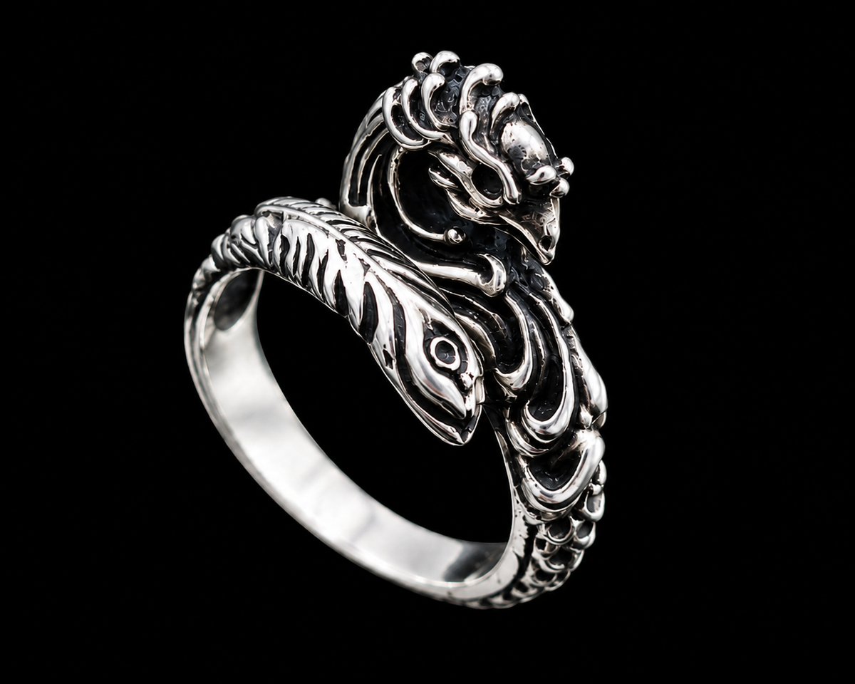 A silver ring with a dragon design on a plain background.