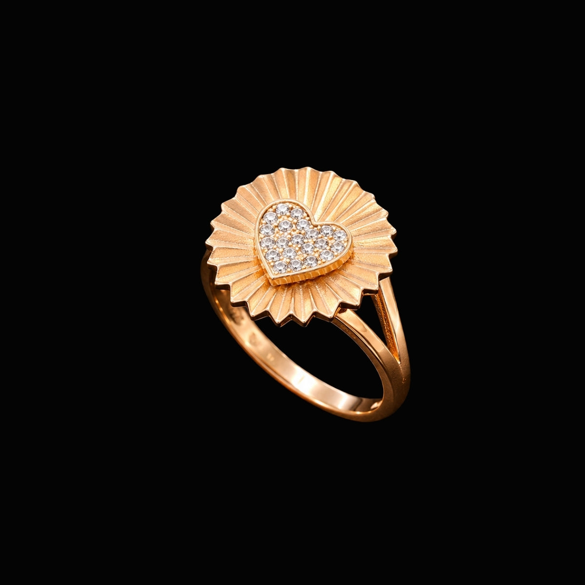 A gold tone ring with a heart motif and CZ stones on a black background.