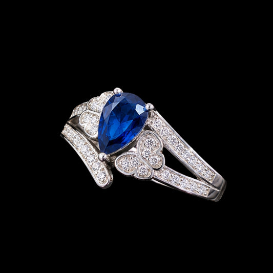 A silver tone ring with a large blue CZ stone and smaller CZ stones