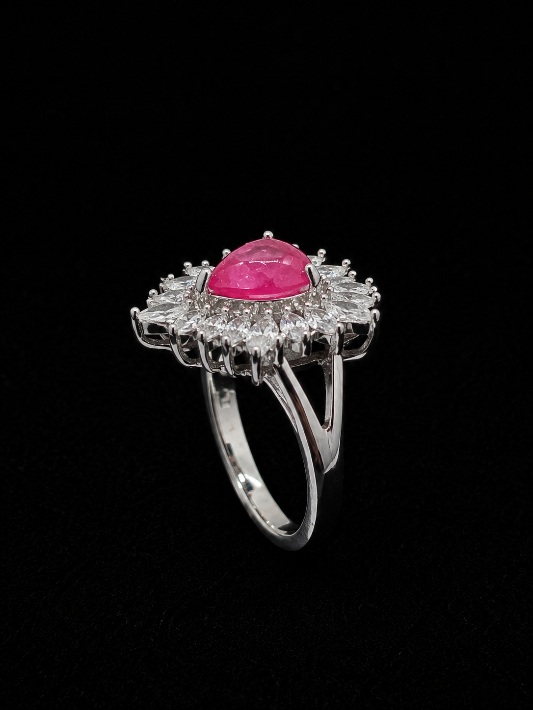 A silver ring with a ruby stone surrounded by CZ stones.