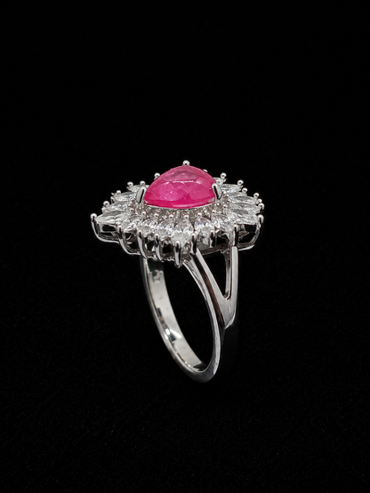 A silver ring with a ruby stone surrounded by CZ stones.