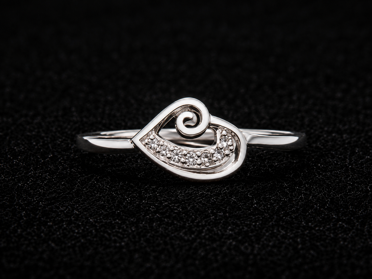 A silver ring with a heart-shaped design and CZ stones on a black background