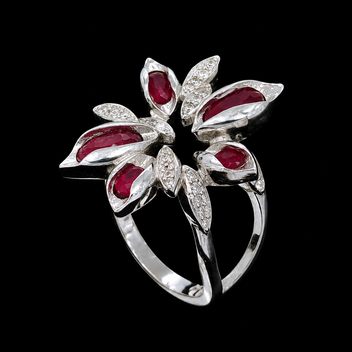 A silver ring with red gemstones in a floral design.
