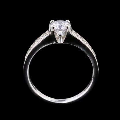 A silver ring with a round-cut CZ stone at its center, set against a plain background.