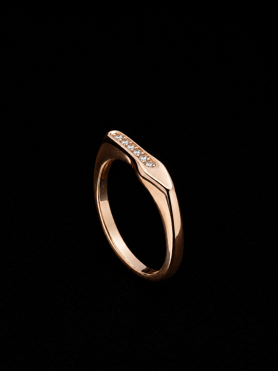 A rose gold ring with clear CZ stones on a black background.