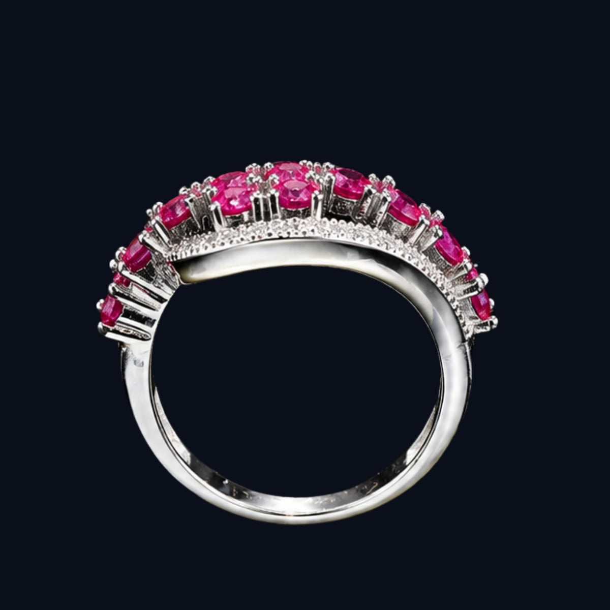 A silver ring with a row of pink CZ stones on a black background