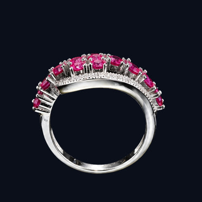 A silver ring with a row of pink CZ stones on a black background