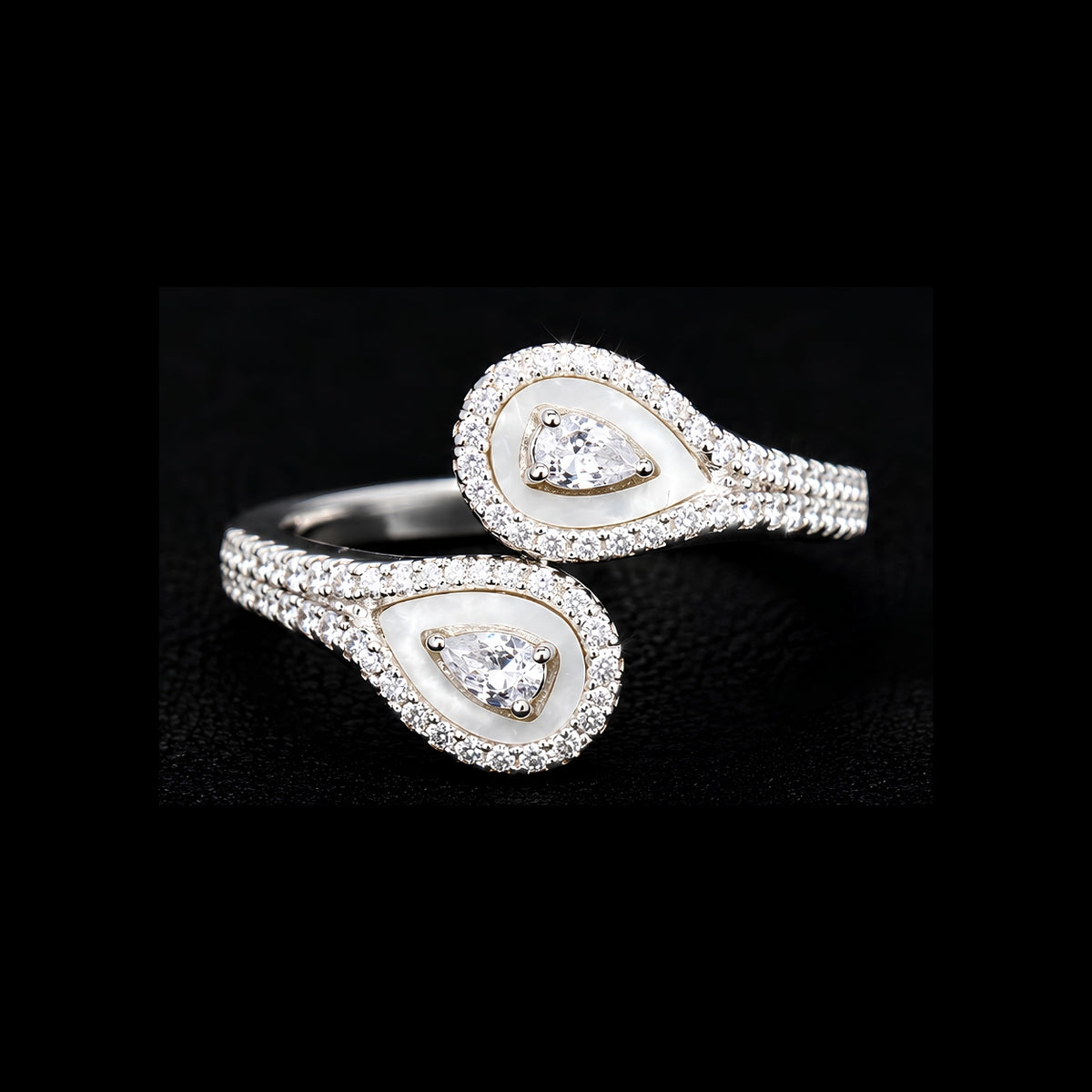 A silver ring with a teardrop design and clear cubic zirconia stones.