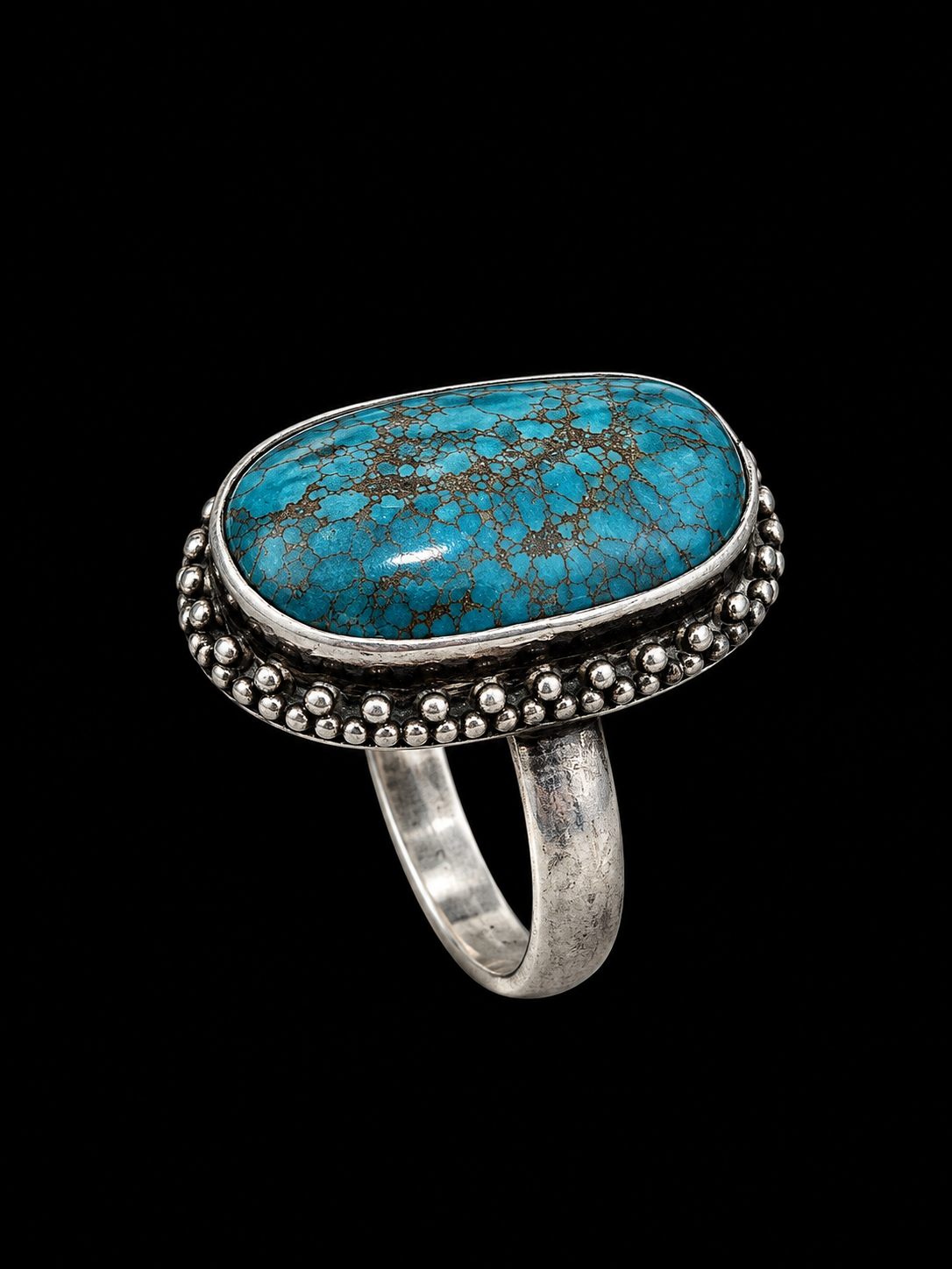 A silver-tone ring with an oval turquoise stone and black matrix pattern.