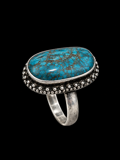 A silver-tone ring with an oval turquoise stone and black matrix pattern.